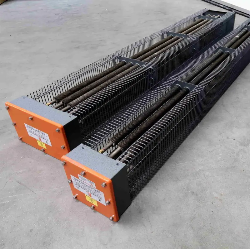 Twee industriële elektrische verwarmingselementen met oranje schakelkasten staan naast elkaar op een grijze betonnen vloer. Elk element heeft een metalen beschermkooi rondom de verwarmingsstaven.