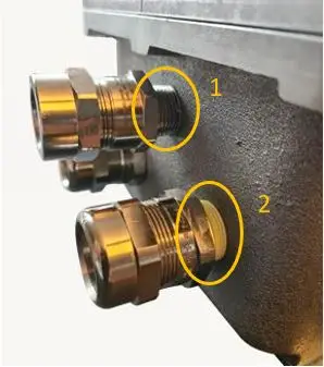Op een donker oppervlak zijn twee metalen kabelwartels bevestigd, die elk zijn gemarkeerd met gele cirkels en voorzien zijn van de nummers 1 en 2 om hun posities aan te geven.