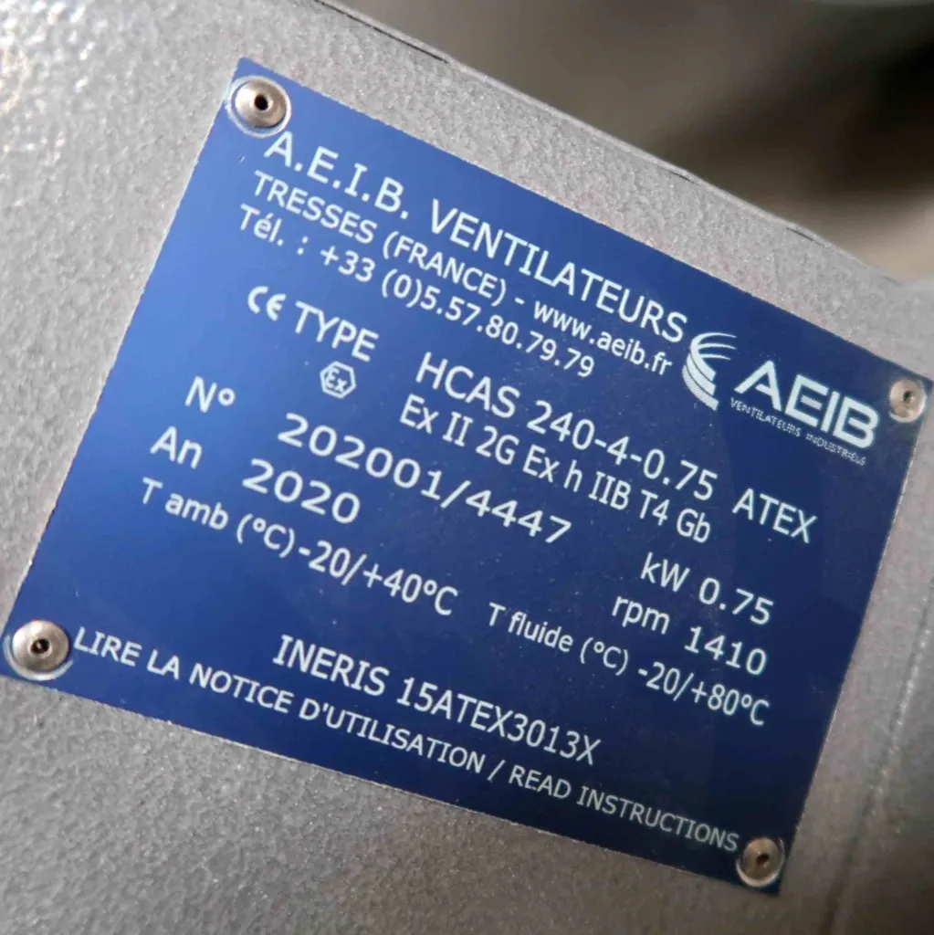 Een blauw metalen typeplaatje met technische specificaties voor een AEIB-beademingsapparaat, waaronder het modelnummer, de certificering, het vermogen, het bouwjaar en de temperatuurbereiken, in het Frans en het Engels.