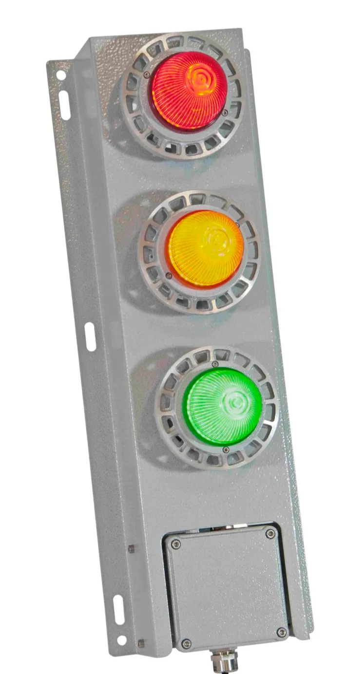 Een verticaal verkeerslicht met brandende rode, gele en groene lampen, bevestigd op een grijs metalen paneel tegen een witte achtergrond.