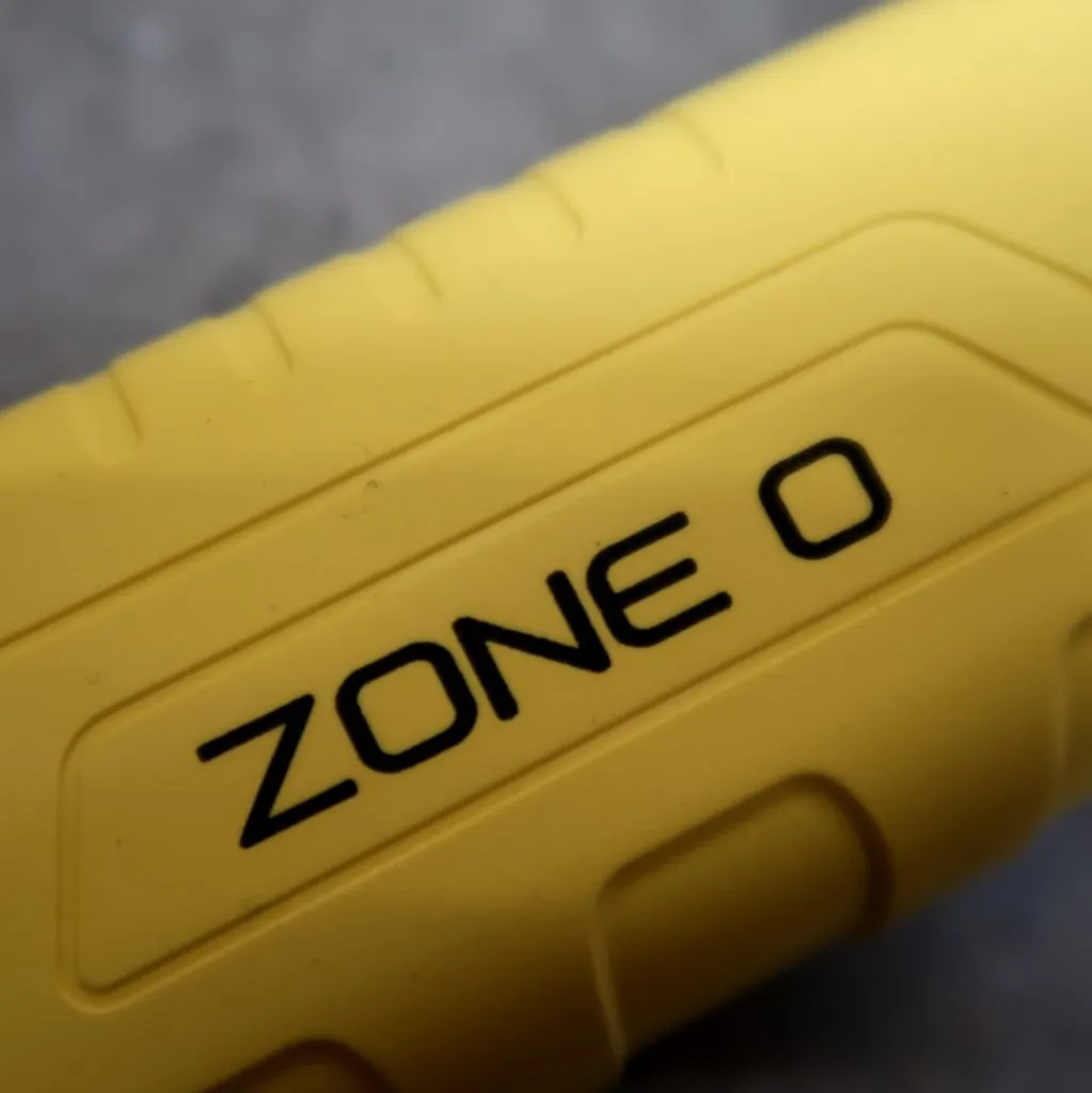 Een close-up van een geel voorwerp waarop in zwarte, reliëfletters op het gestructureerde oppervlak de woorden ZONE 0 staan.